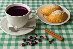 Vaso de api morado con canela y clavo en mesa de madera