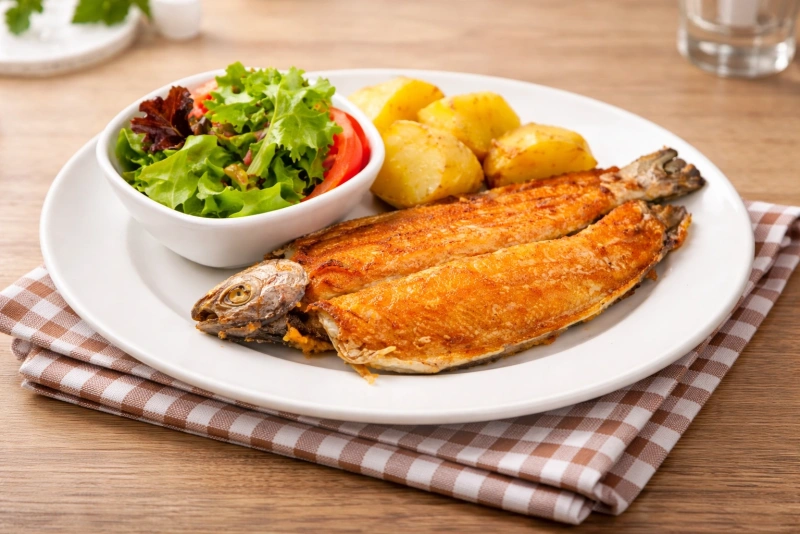 Deliciosa trucha frita andina servida con papas doradas y ensalada fresca.